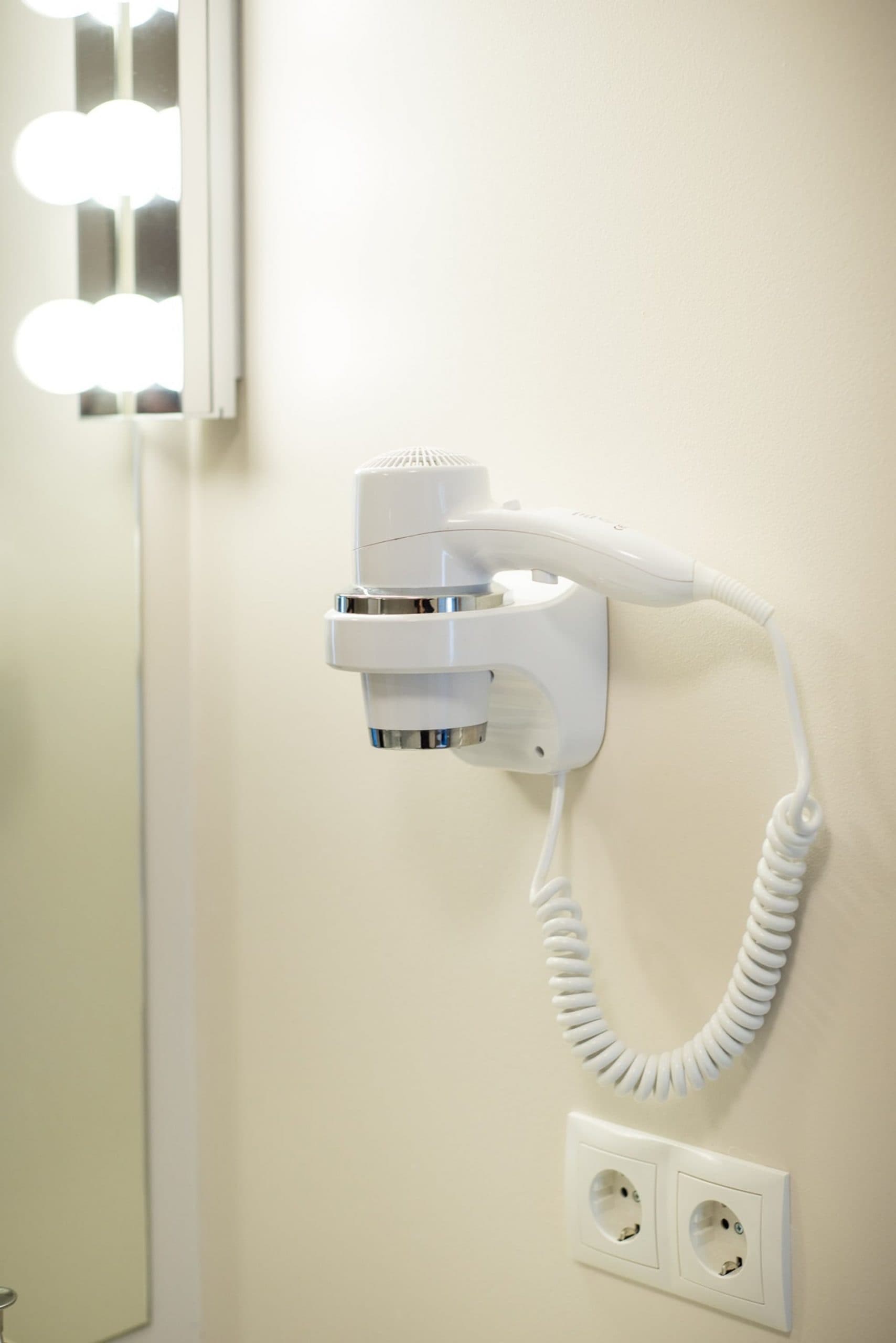 Wall mounted hairdryer by the mirror