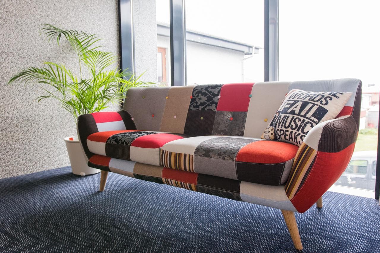 Patchwork sofa with a music themed cushion by a large window