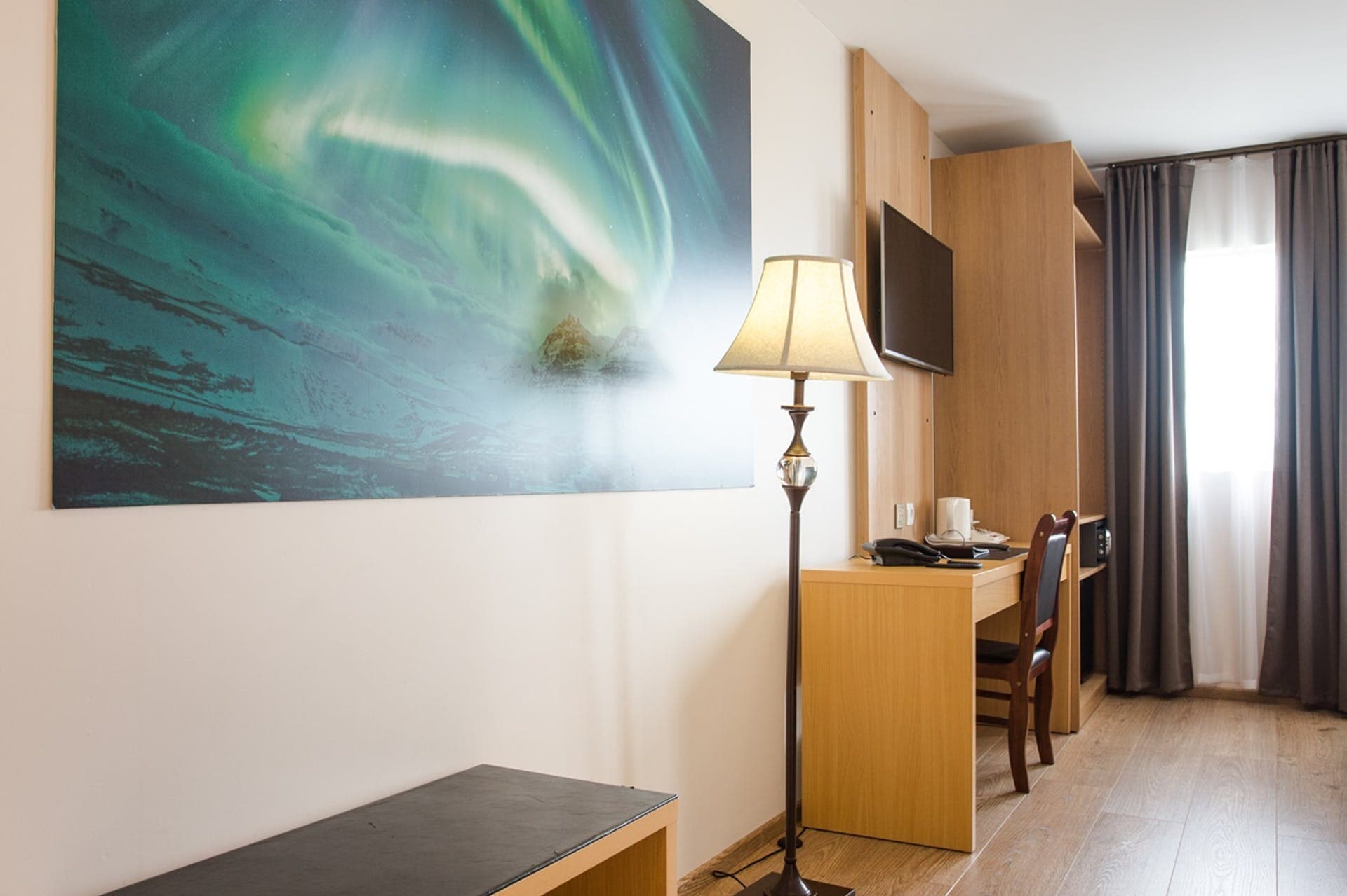 Room with a northern lights print, a floor lamp and a desk