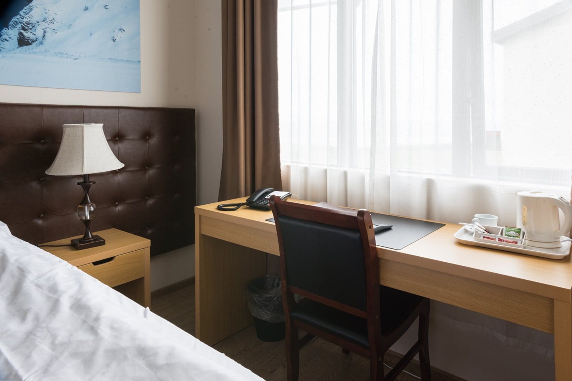 Desk with a phone, a kettle and a tea tray beside the bed