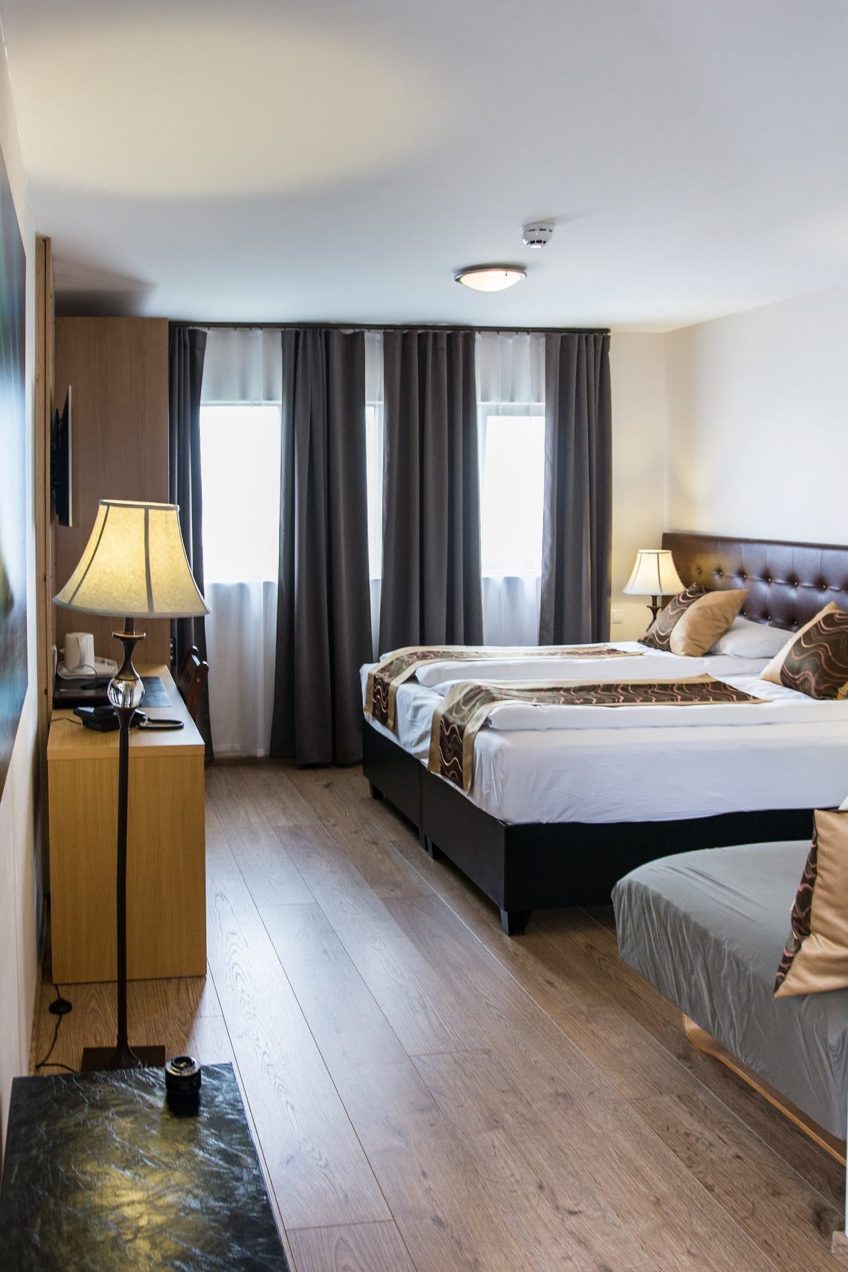 Long triple room with a large bed, a single bed and a floor lamp