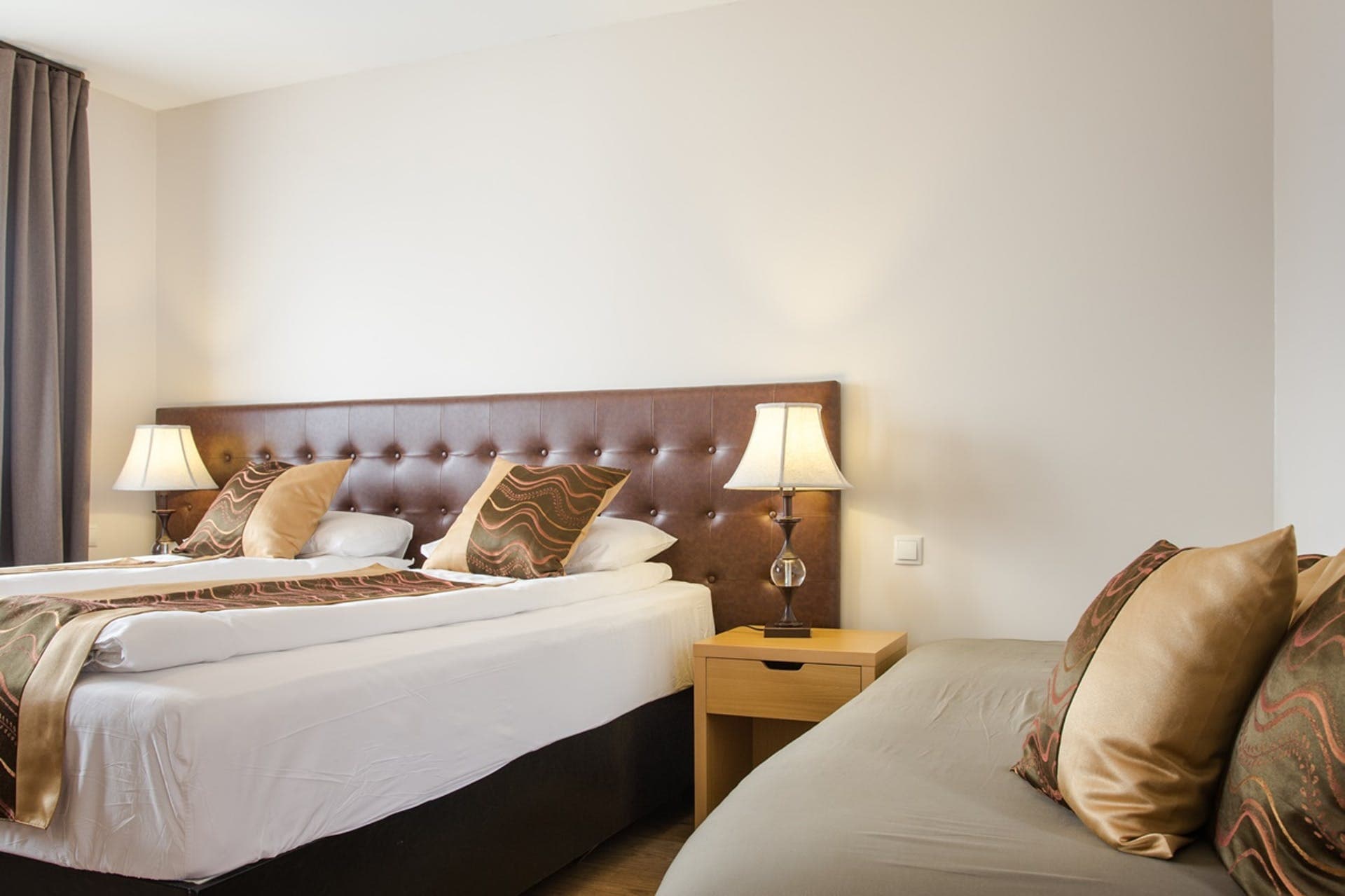 Triple room with a large bed and a single bed under padded headboards