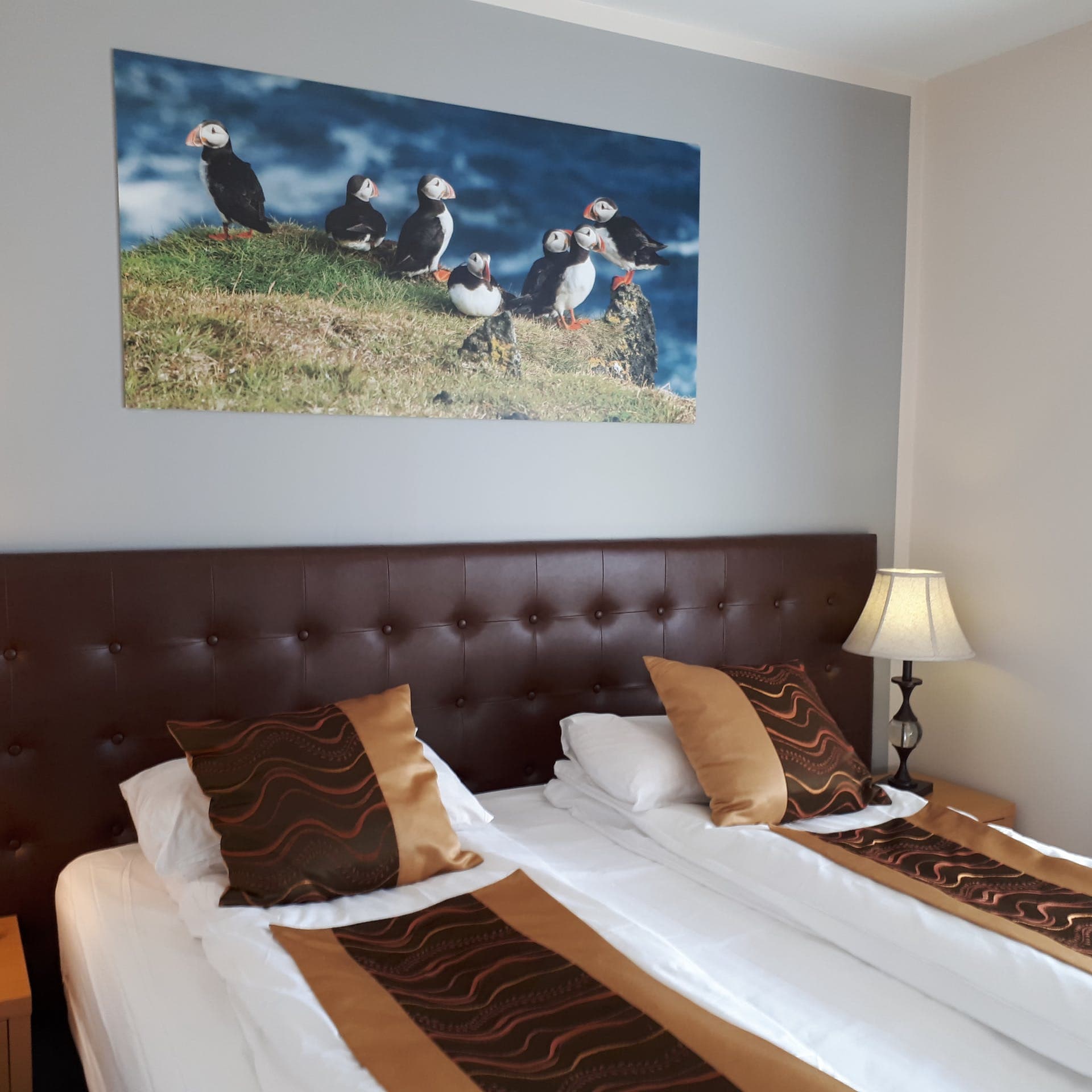 Two beds side by side under a print of puffins